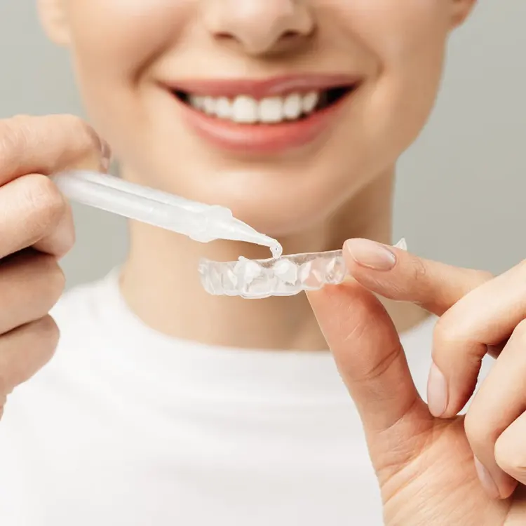 ragazza sorridente con kit per sbiancamento dentale